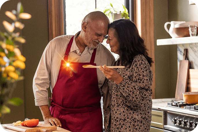 Two adults standing together in a kitchen preparing food