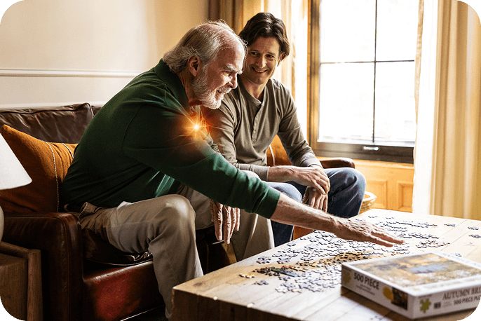 Two adults sitting together at a table working on a puzzle at home